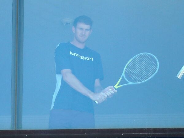 A tennis player practices with a racket inside a room at a hotel where players are undergoing mandatory quarantine in advance of the Australian Open in Melbourne, Australia, January 21, 2021